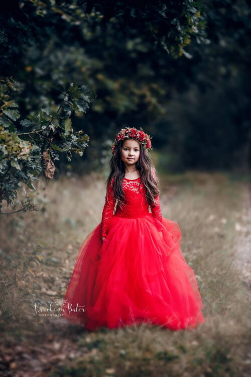 Girl wearing a lace top tulle gown standing in a forest path