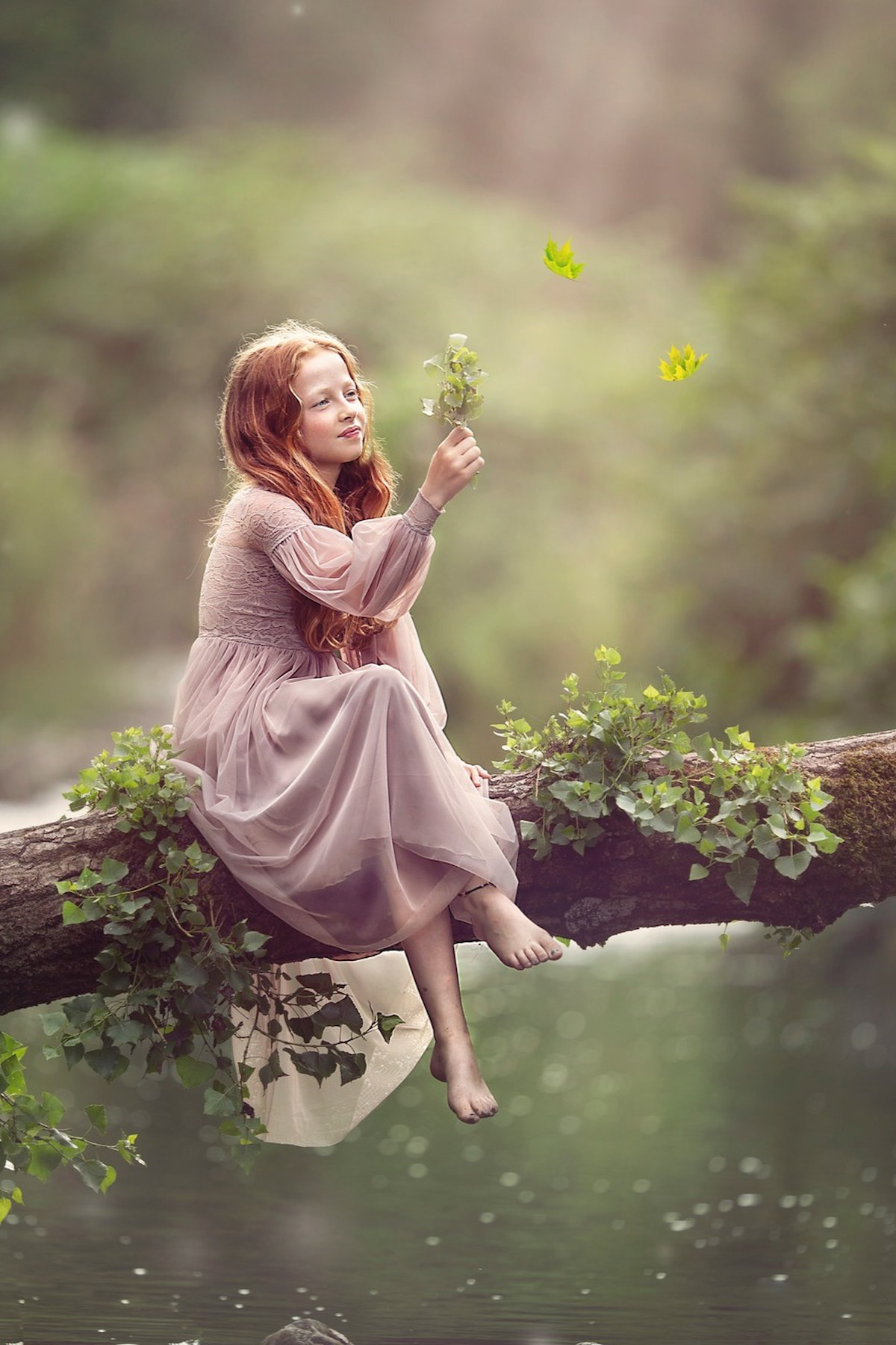 Child in a long sleeve lace dress sitting on a tree branch over water