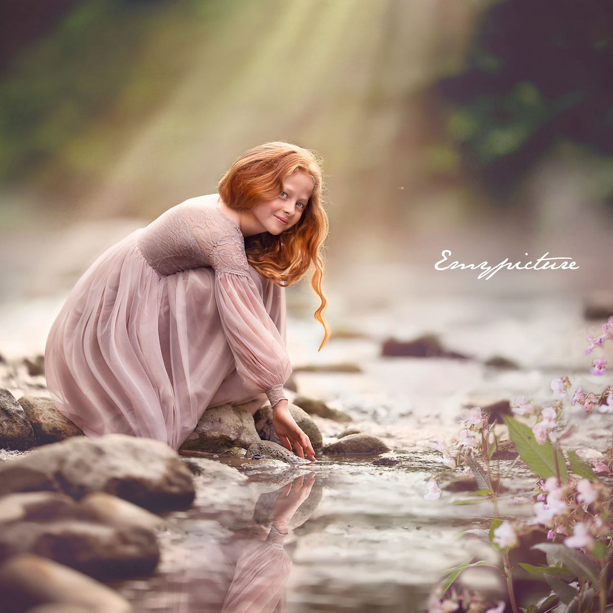 Child in a long sleeve lace dress sitting on a tree branch over water