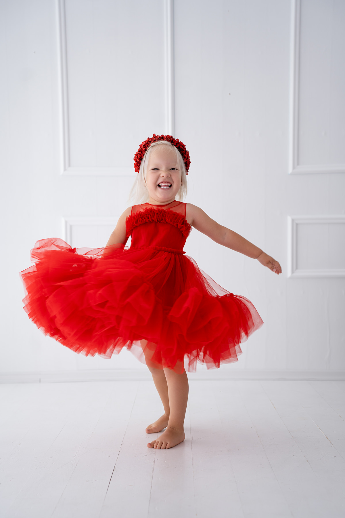 Toddler girl twirling in a tulle dress in a bright studio setting