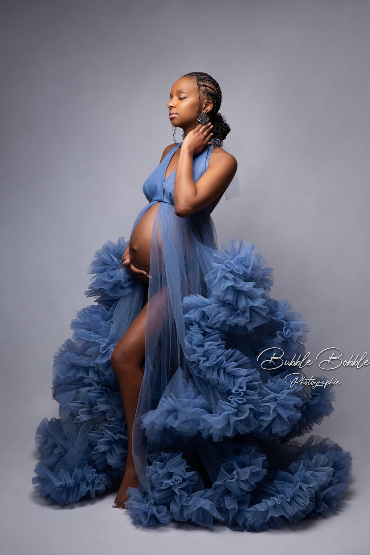 Maternity photoshoot with model wearing Rumba dress in denim blue, featuring fitted silhouette and voluminous tulle train.