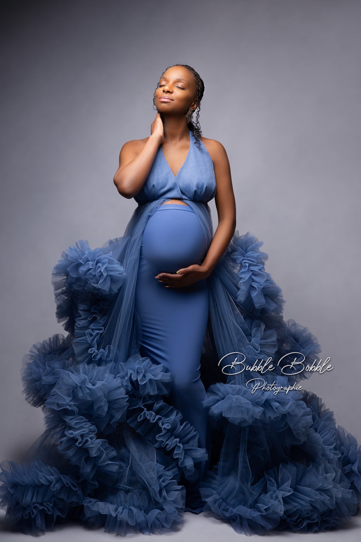 Elegant maternity photoshoot styling with Rumba dress in denim blue, soft tulle fabric and flowing ruffles creating dreamy effect.
