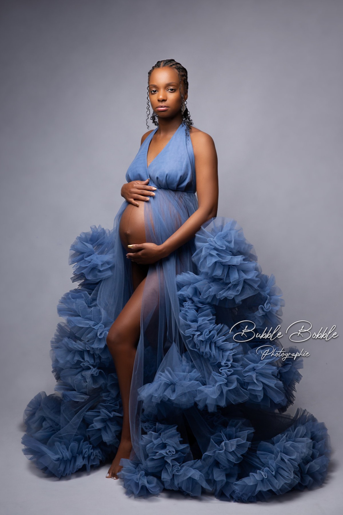 Rumba tulle gown in denim blue used for maternity photoshoot, featuring fitted top and voluminous ruffled skirt.