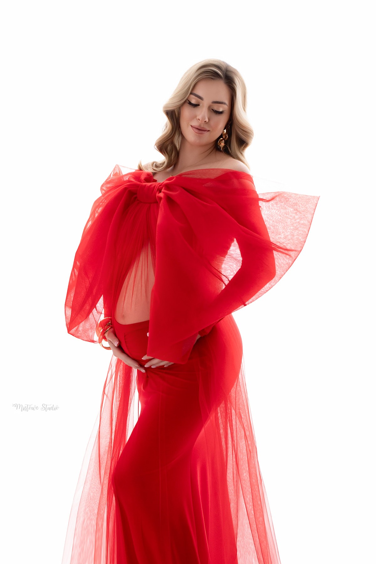 Sheer red tulle bow with long flowing train used as maternity photoshoot accessory