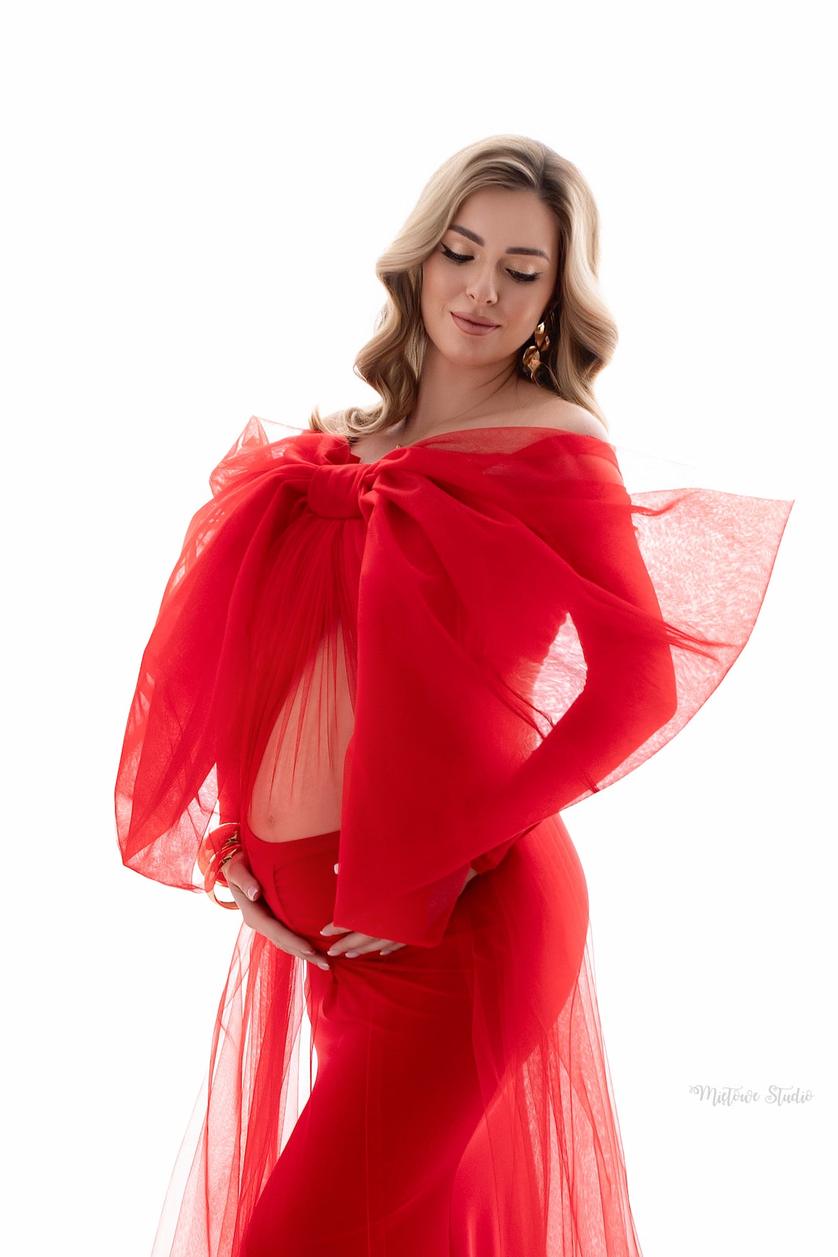 Close-up of oversized red tulle bow draped over shoulders in maternity styling
