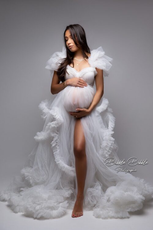 Pregnant woman wearing Kara tulle dress with underwired corset and soft ruffles in studio