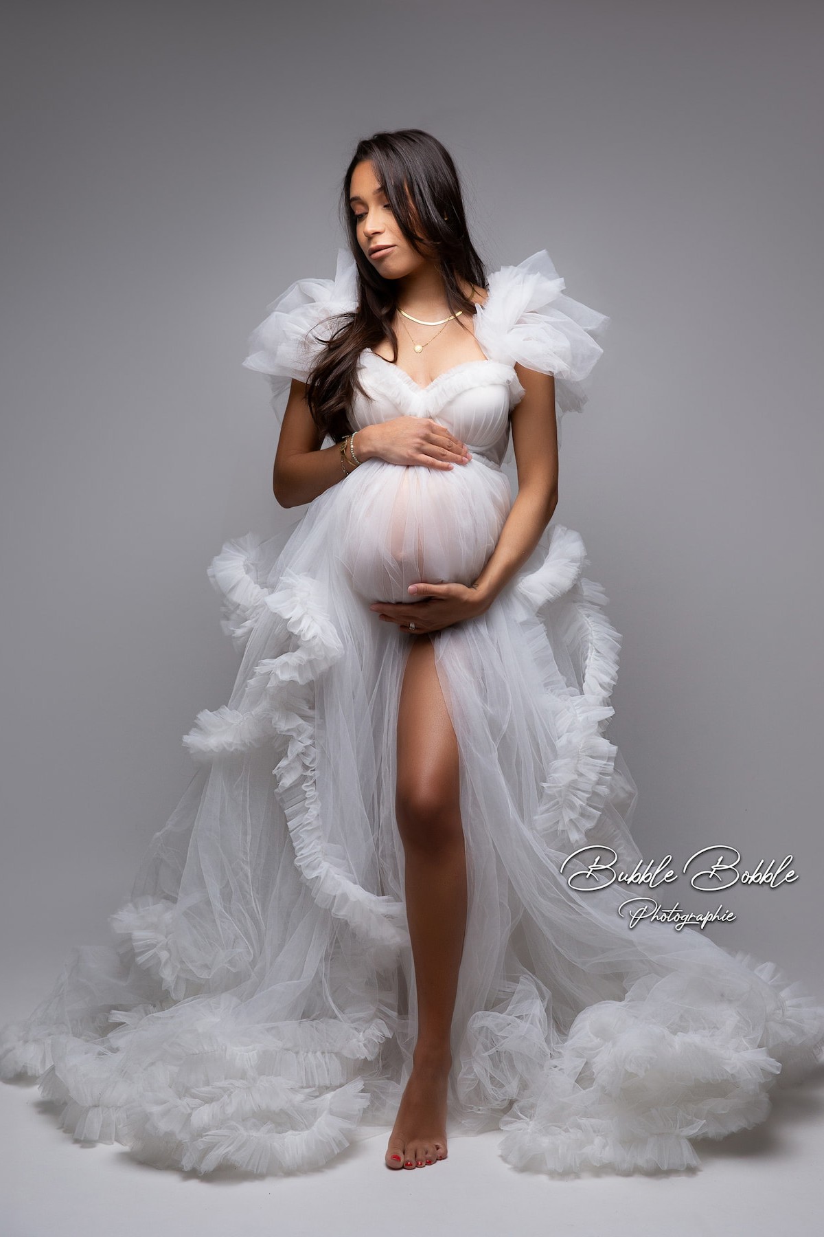 Pregnant woman wearing Kara tulle dress with underwired corset and soft ruffles in studio