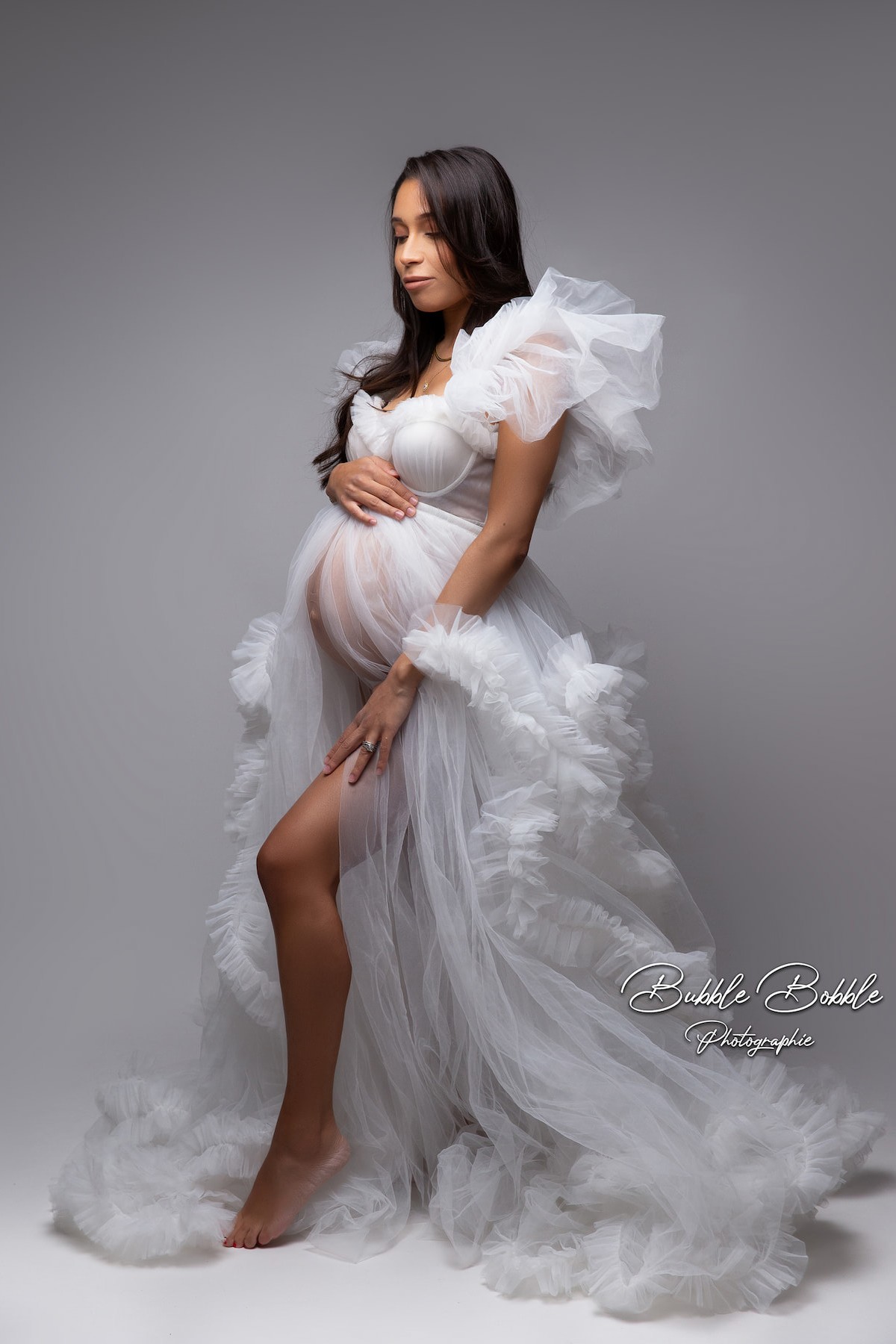 Side view of maternity model in Kara dress with front slit and flowing tulle skirt